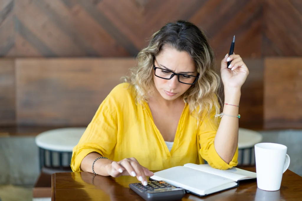 Mulher mexendo na calculadora representando contador declarando imposto de renda